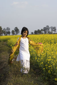 Girl standing on field against sky