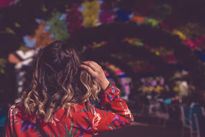 Rear view of woman with brown wavy hair in city