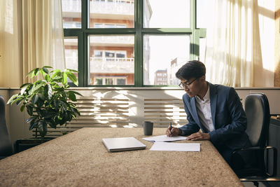 Side view of young man using digital tablet while sitting at home
