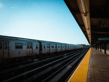 Train at railroad station against clear blue sky