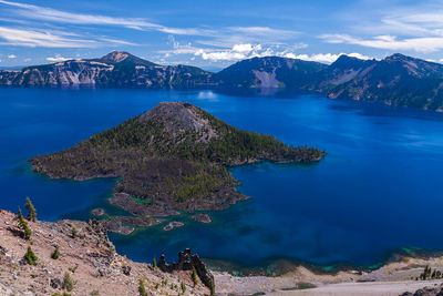 Scenic view of sea and mountains against blue sky