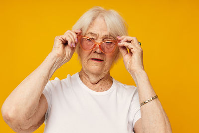 Portrait of senior woman wearing novelty glasses against colored background