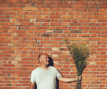 Man standing against brick wall