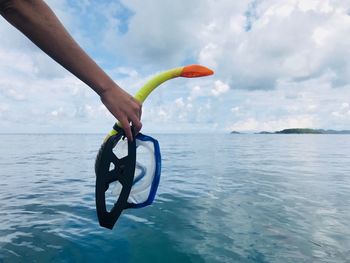 Cropped hand of woman holding scuba mask over sea