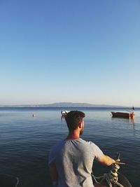 Rear view of man standing by sea against sky