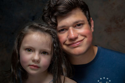 Portrait of smiling brother with cute sister against wall