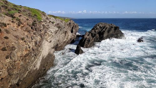 Rock formation in sea against sky