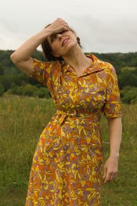 Young woman looking away while standing on field