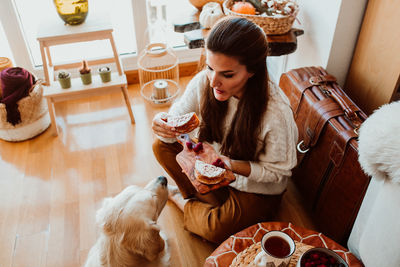 High angle view of woman feeding dog while sitting at home