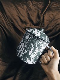 A patterned green glass held by a woman's hand