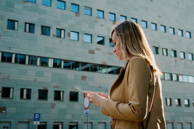 Beautiful woman using smartphone at city street, caucasian female portrait using mobile phone