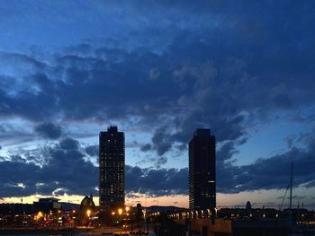 Low angle view of illuminated cityscape against cloudy sky