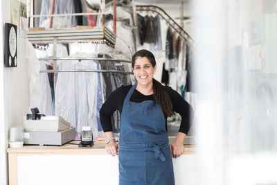 Portrait of smiling mature female owner standing at laundromat