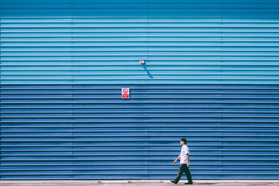 Man walking by blue shutter in sunny day