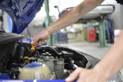 Car mechanic in a workshop checking motor oil