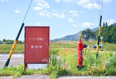 Information sign on grass against sky