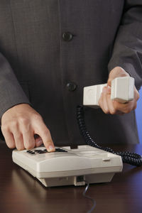 Midsection of businessman holding telephone