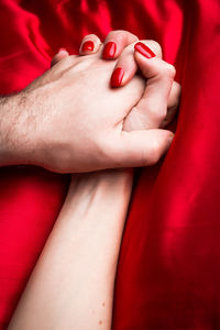 Cropped image of couple holding hands on bed