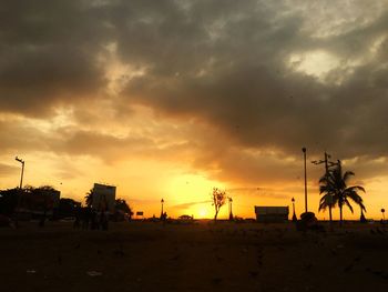 Silhouette palm trees on beach against sky at sunset