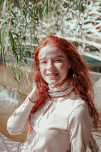 Portrait of smiling teenage girl sitting on retaining wall