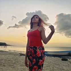Young woman standing at beach during sunset