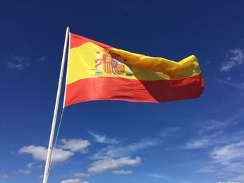 Low angle view of national flag of spain against sky