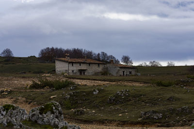 House on field by building against sky