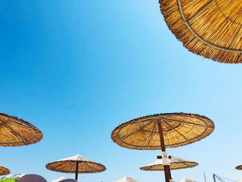 Low angle view of umbrellas against clear blue sky