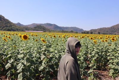 Portrait of woman standing against sunflower field during sunny day