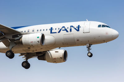 Low angle view of airplane flying against clear blue sky