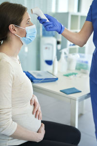 Midsection of nurse taking temperature of patient