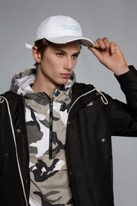 Portrait of young man standing against gray background