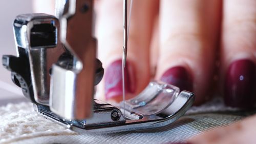 Cropped hand of tailor using sewing machine while stitching textile