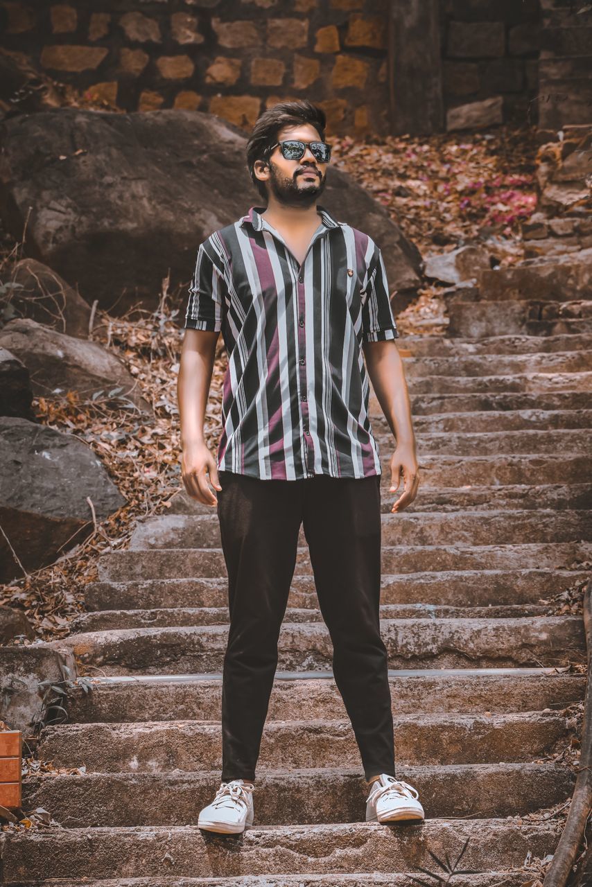 one person, spring, young adult, fashion, standing, front view, adult, casual clothing, black, portrait, full length, glasses, men, lifestyles, architecture, leisure activity, photo shoot, sunglasses, clothing, nature, hipster, hands in pockets, outdoors, cool attitude, looking, day, looking at camera, teenager