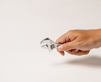 Cropped hand of person holding bitcoin against white background