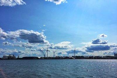 Traditional windmill by lake against sky