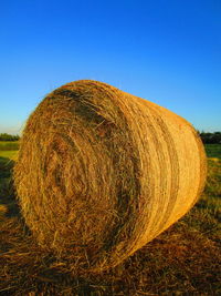 Hay bales on field against clear sky