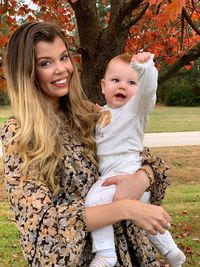 Portrait of happy mother and daughter on tree against plants