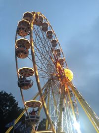 Low angle view of illuminated ferris wheel against cloudy sky