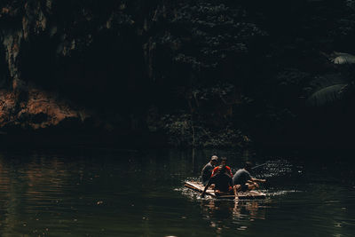Men sitting on raft in lake
