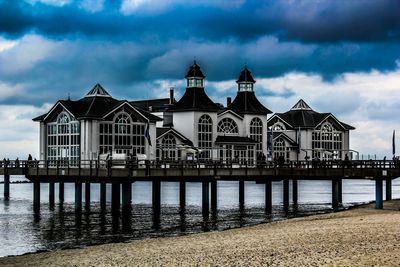 View of building by river against cloudy sky