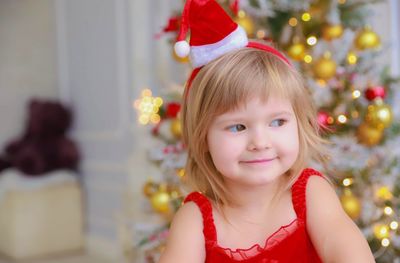 Cute smiling girl looking away against christmas tree