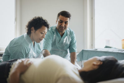 Male and female surgeons examining patient in hospital