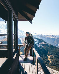 Man standing on railing by mountain against sky