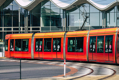 Red train on street by building in city