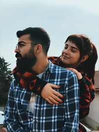 Portrait of young couple kissing against sky