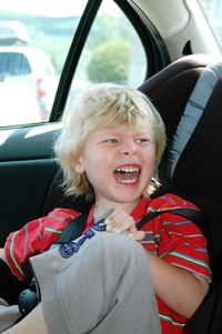 Cute cheerful boy looking away while sitting in car