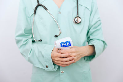 Midsection of doctor holding stethoscope against white background