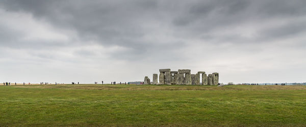 Buildings in field against cloudy sky