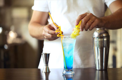 Midsection of bartender preparing drink on table